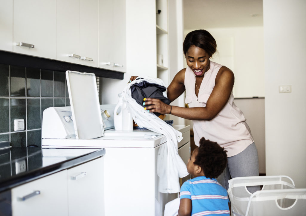 African descent kid helping mom doing the laundry African descent kid helping mom doing the laundry
